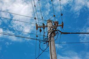 lignes électriques de poteau électrique fils électriques sortants contre le ciel bleu nuageux. photo