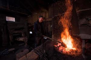 jeune forgeron traditionnel travaillant avec feu ouvert photo