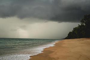 plage tropicale avec sable blanc et nuages d'orage sombres. photo