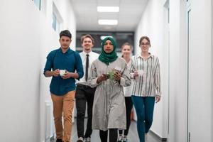 une équipe commerciale de démarrage multiethnique marchant dans le couloir de l'immeuble en revenant d'une pause-café photo