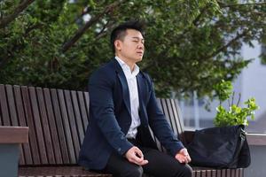 homme d'affaires asiatique effectuant des exercices de respiration essayant de calmer le stress photo