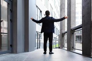 homme d'affaires prospère lève les mains en signe de victoire et de succès près de photo