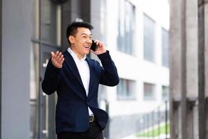 homme d'affaires asiatique parlant au téléphone joyeux souriant rapporte de bonnes nouvelles photo