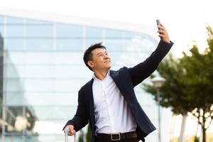 un homme d'affaires touristique asiatique arrivé à une conférence d'affaires prend des photos près de l'aéroport