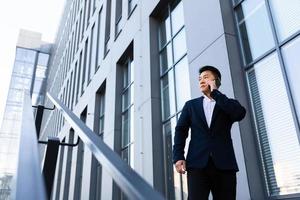 homme d'affaires asiatique sérieux et prospère parlant au téléphone près du centre de bureau photo