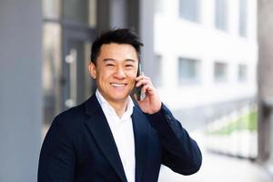 portrait, homme affaires asiatique, parler téléphone, gai, sourire, rapports, bonnes nouvelles photo