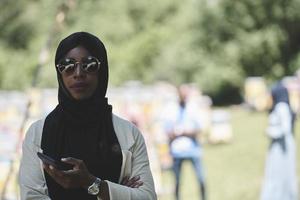 femme africaine utilisant un smartphone portant des vêtements islamiques traditionnels photo