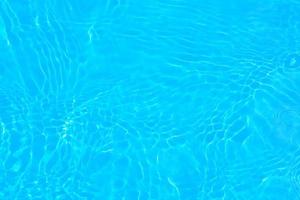 défocalisation floue transparente couleur bleue claire texture de surface de l'eau calme avec éclaboussures, bulle. fond d'ondulation de l'eau bleue brillante. surface d'eau dans la piscine. eau de bulle bleue qui brille. photo