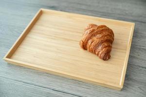 servant des croissants croustillants cuits au four sur un plateau en bois. photo