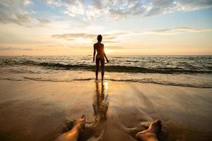 silhouette de femme sur la plage au coucher du soleil avec des jambes d'homme. photo