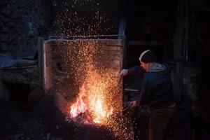 jeune forgeron traditionnel travaillant avec feu ouvert photo