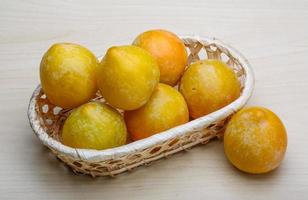 prunes jaunes dans un panier sur fond de bois photo