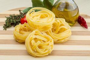 fettuccine crue sur planche de bois et fond en bois photo