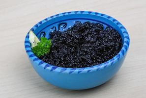 caviar noir dans un bol sur fond de bois photo