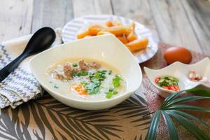 bouillie de style chinois ou bouillie et bâtonnet de pâte frite ou bâtonnet de pâte frite ou beignet ou pain frit placé sur une table en bois. La cuisine de rue thaïlandaise s'appelle le porridge et le patongo. photo