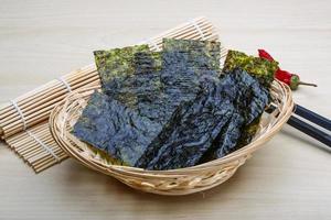 Feuilles de nori dans un panier sur fond de bois photo