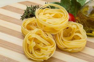 fettuccine crue sur planche de bois et fond en bois photo