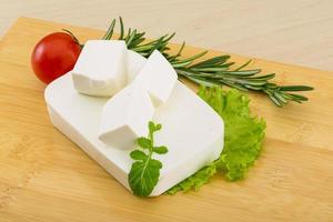 Fromage feta sur planche de bois et fond de bois photo