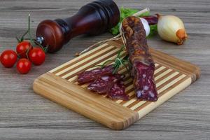 saucisse de salami sur planche de bois et fond de bois photo