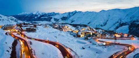 paysage d'hiver pittoresque à gudauri avec fond de montagnes du caucase et hôtels de vacances et route avec des voitures le soir photo