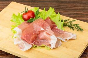 Prosciutto sur planche de bois et fond de bois photo