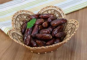 Dates fruits dans un panier sur fond de bois photo