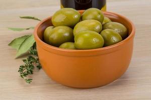 olives vertes dans un bol sur fond de bois photo