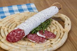 Saucisse fuet sur planche de bois et fond de bois photo