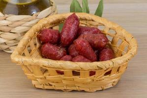 Mini salami dans un panier sur fond de bois photo