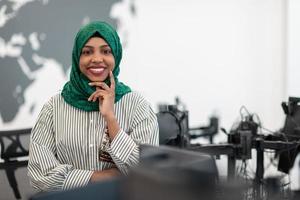 portrait d'une femme noire musulmane développeur de logiciels avec hijab vert debout dans un bureau de démarrage moderne à plan ouvert. mise au point sélective photo