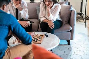 groupe multiethnique de gens d'affaires jouant aux échecs tout en faisant une pause dans l'espace détente du bureau de démarrage moderne photo