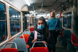 jeune femme avec masque voyageant dans les transports en commun. photo