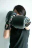 une femme portant des gants de boxe noirs tendant son poing gauche vers la cible avant. photo