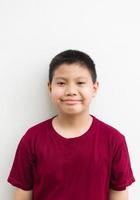 portrait d'un petit garçon asiatique fossette debout souriant joyeusement geste confiant sur fond blanc photo