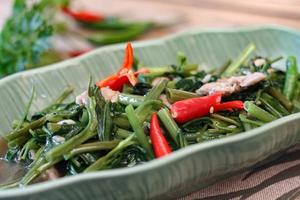 La gloire du matin sautée dans un plat noir La gloire du matin sautée est également l'un des plats les plus délicieux que vous puissiez manger en Thaïlande. photo