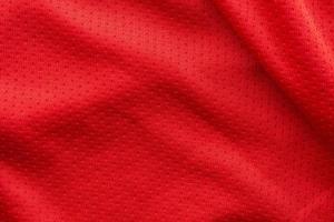 maillot de football de vêtements de sport en tissu rouge avec fond de texture en maille d'air photo