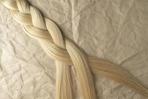 une tresse de cheveux blonds allongée sur un papier kraft marron photo
