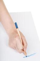 La main dessine au crayon bleu en bois sur une feuille de papier photo
