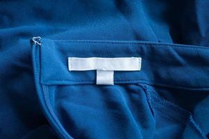 étiquette de vêtements de soin du linge blanc vierge sur robe bleue photo