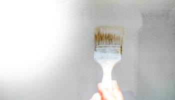 la main féminine utilise la peinture au pinceau, le travailleur peint sur le mur de surface en acier par la brosse à rouleau pour la protection et la corrosion. photo