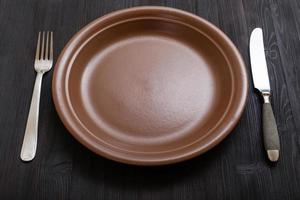 assiette marron avec couteau, cuillère sur table marron foncé photo