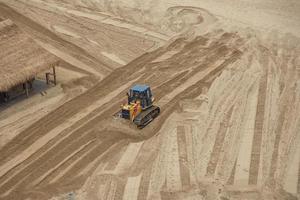 le bulldozer aplatit le sable de la plage. vue de dessus photo