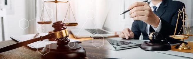 concept de justice et de droit. juge masculin dans une salle d'audience avec le marteau, travaillant avec, clavier d'ordinateur et d'accueil, lunettes, sur table à la lumière du matin photo