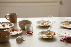 vider les assiettes sales avec des cuillères et des fourchettes sur la table après le repas. concept de fin de banquet. vaisselle non lavée photo