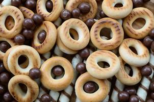 beaucoup de tubules sucrés croustillants, de boules fondantes au chocolat et de bagels jaunes reposent sur une surface en bois. vue rapprochée photo