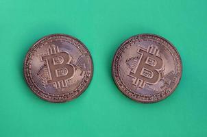 deux produits au chocolat sous forme de bitcoins physiques se trouvent sur un fond en plastique vert. modèle de la crypto-monnaie sous forme comestible photo