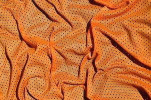 fond de texture de tissu de vêtements de sport orange. vue de dessus de la surface textile en tissu orange. maillot de basket lumineux. espace de texte photo