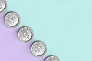 De nombreuses canettes de bière métalliques sur fond de texture de papier de couleurs pastel violet et bleu mode dans un concept minimal photo