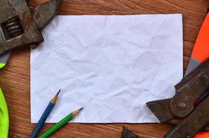 une feuille de papier froissée avec deux crayons entourés d'uniformes de travail verts et oranges et de clés à molette photo