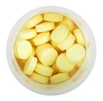 Pilules jaunes dans une bouteille en plastique ronde en gros plan photo